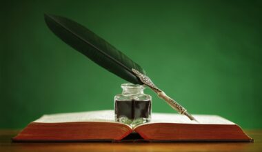 Quill pen and inkwell resting on an old book with green background