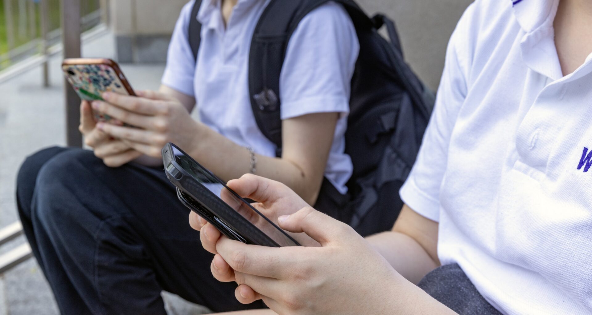 Two students sit and look at their cell phones.