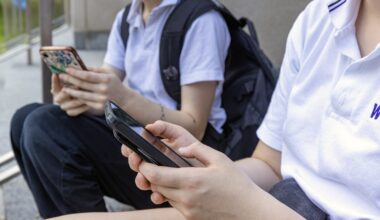 Two students sit and look at their cell phones.