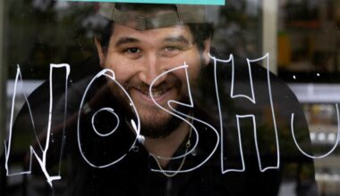 A Montreal restaurant owner in his storefront window that displays the word nosh.