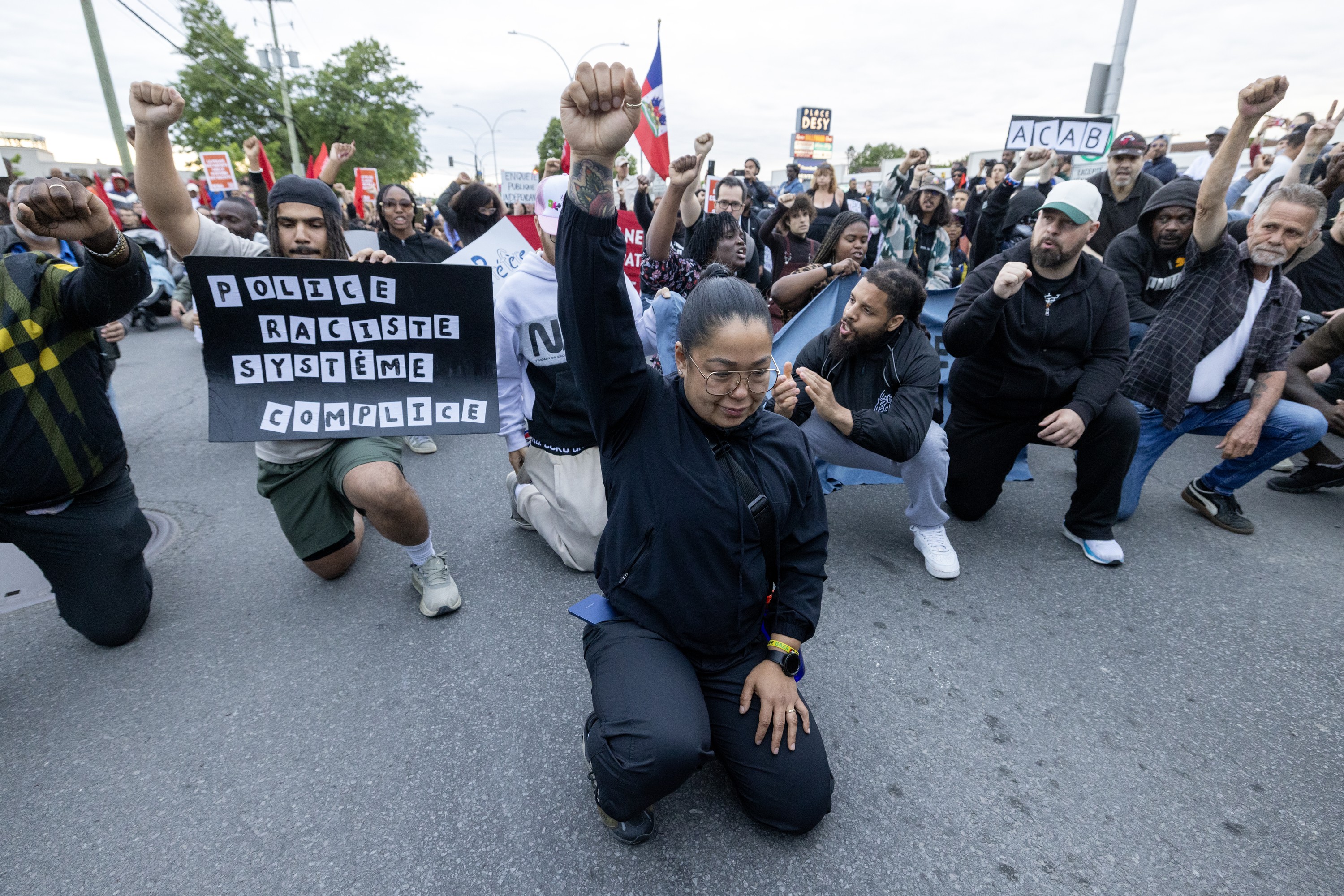 Anti-racism protesters kneel in the street.