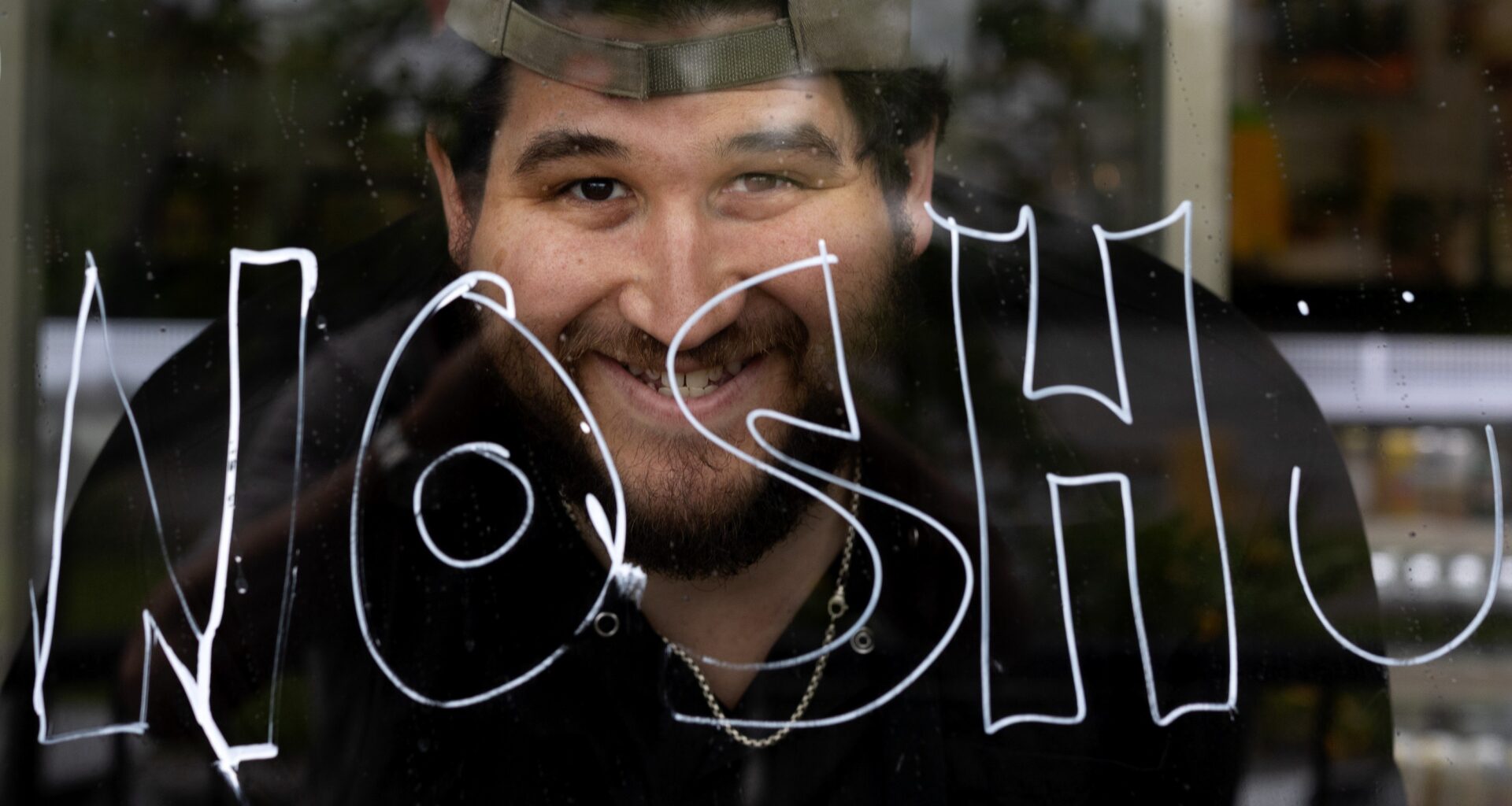 Benjamin Greenberg, owner of Yans Deli, displays the word "nosh" on his storefront window in support of Arthur’s Nosh Bar
