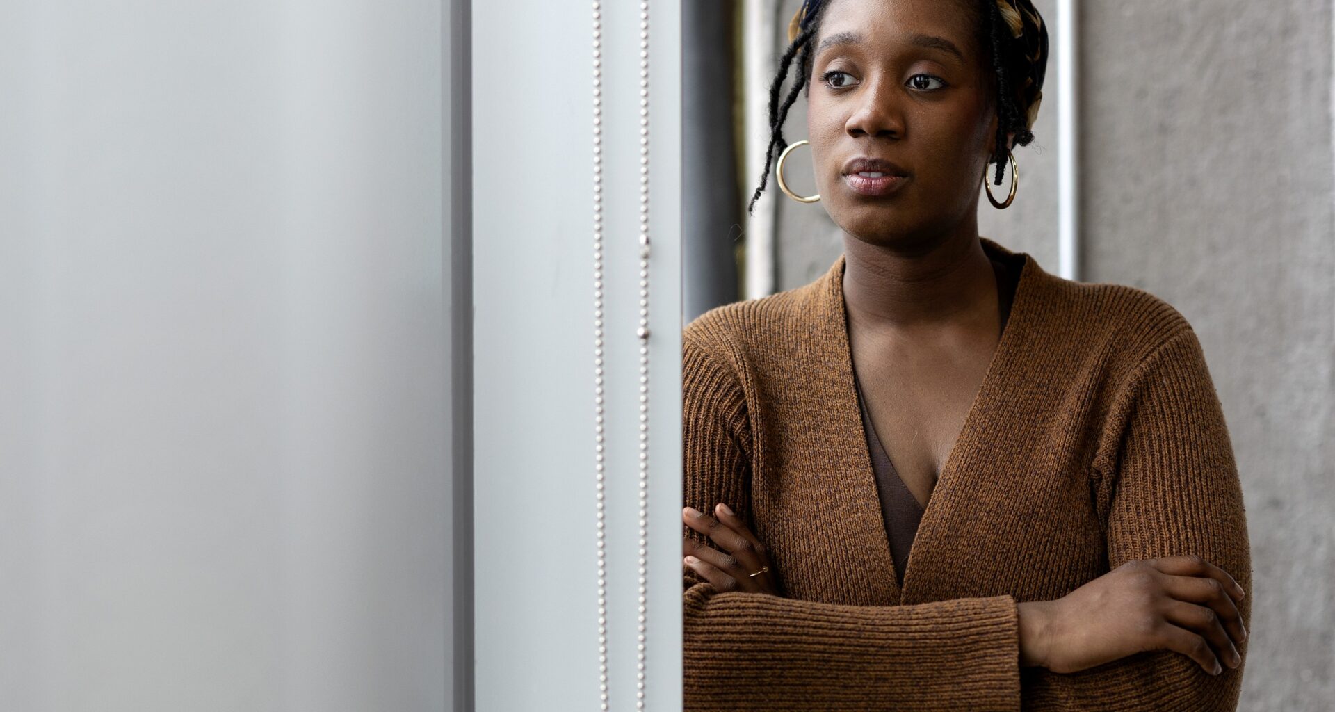 A woman looks pensive as she peers out a window.