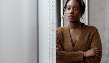 A woman looks pensive as she peers out a window.