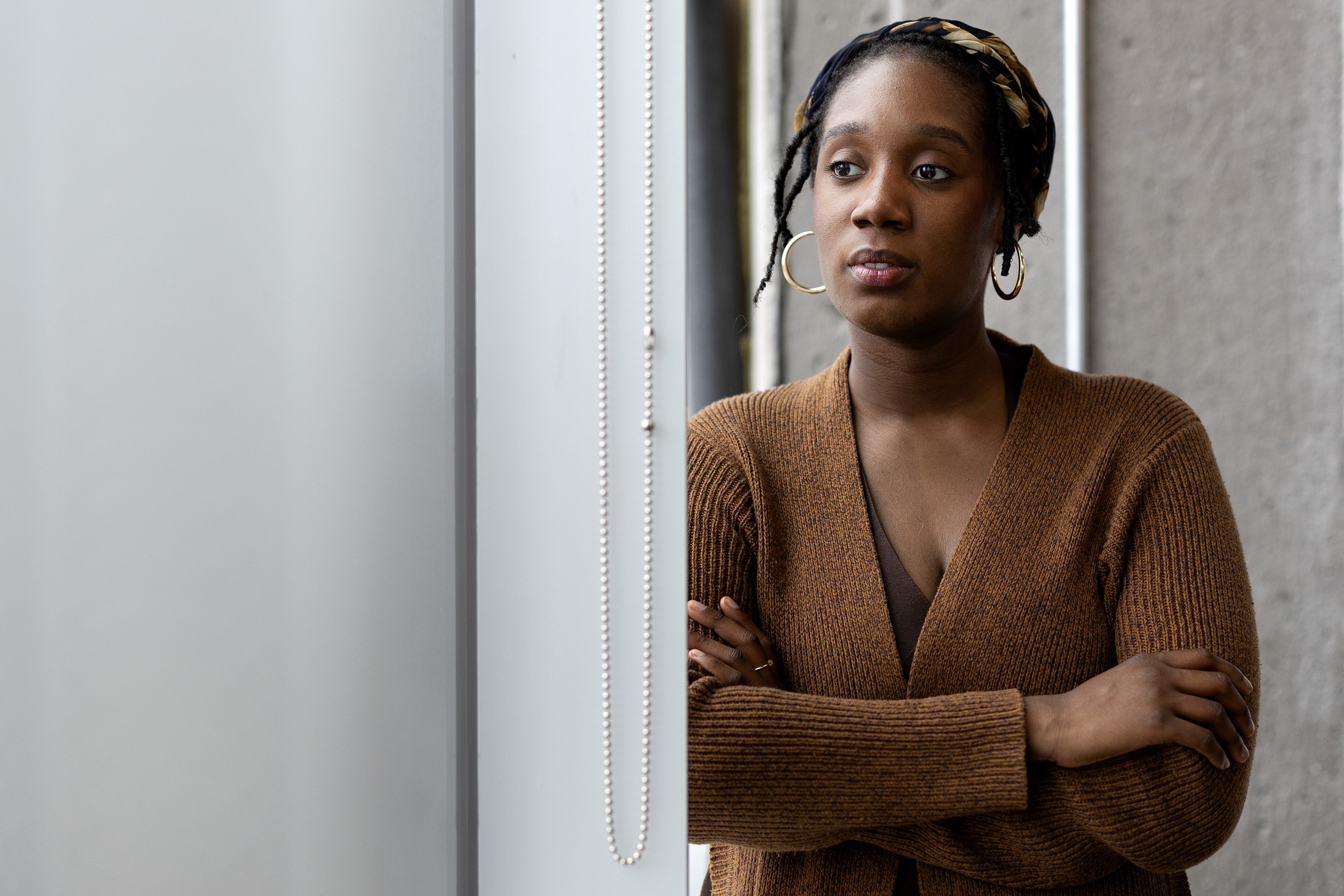 A woman looks pensive as she peers out a window.