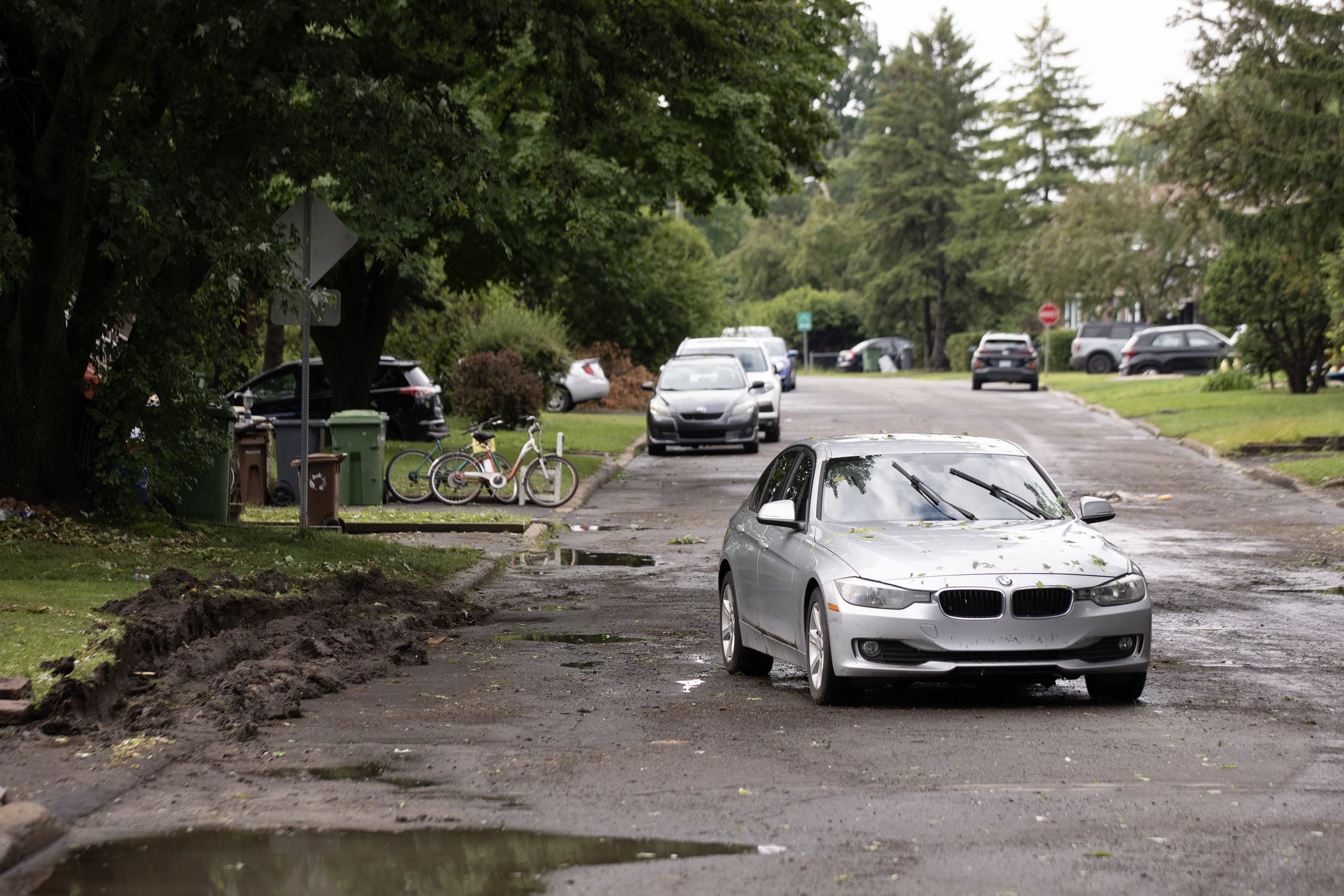An abandoned BMW sits in the middle of a street.