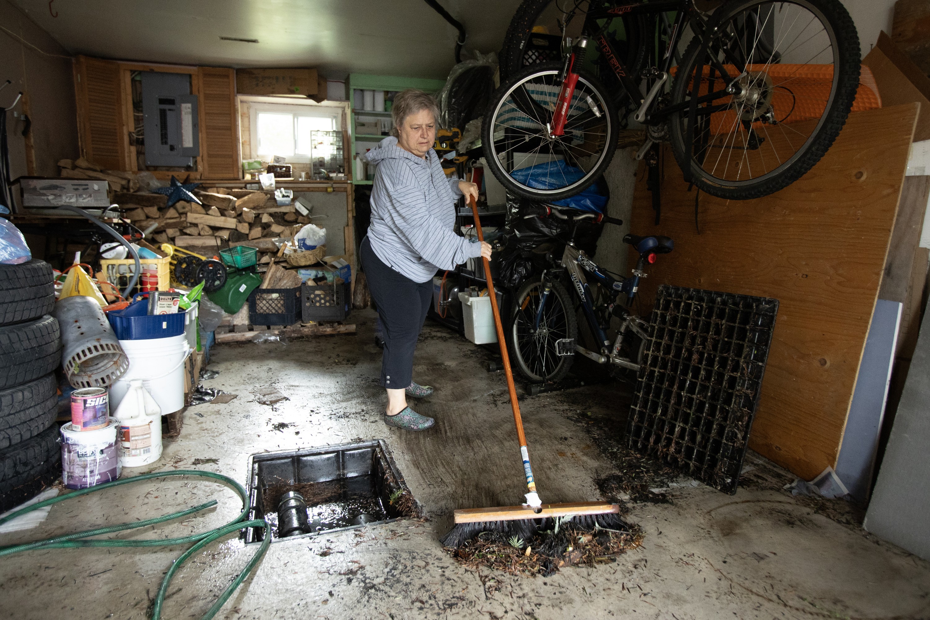 A woman sweeps debris in a garage.