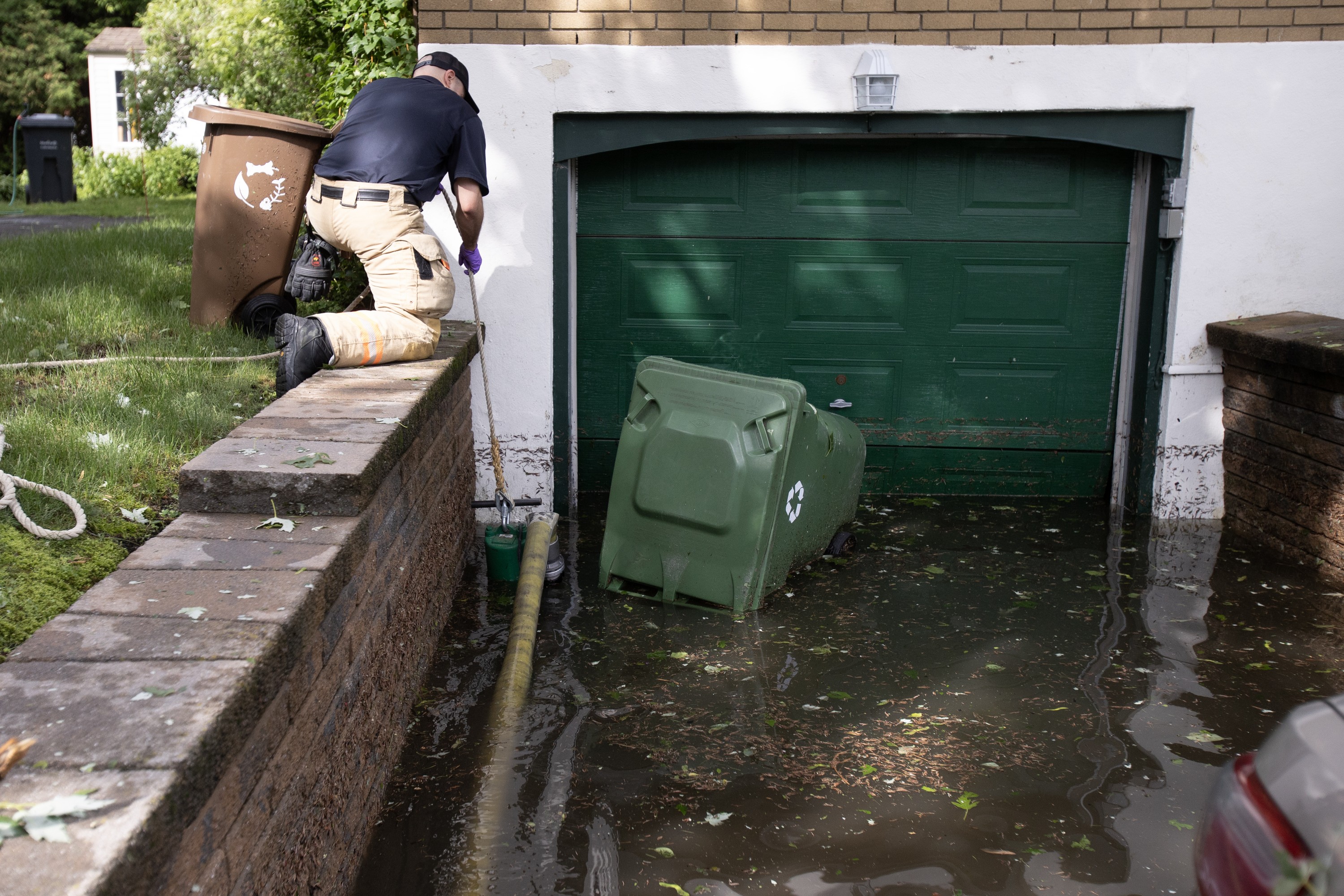 A Montreal firefighter is seen from behind as he pumps water from a house.