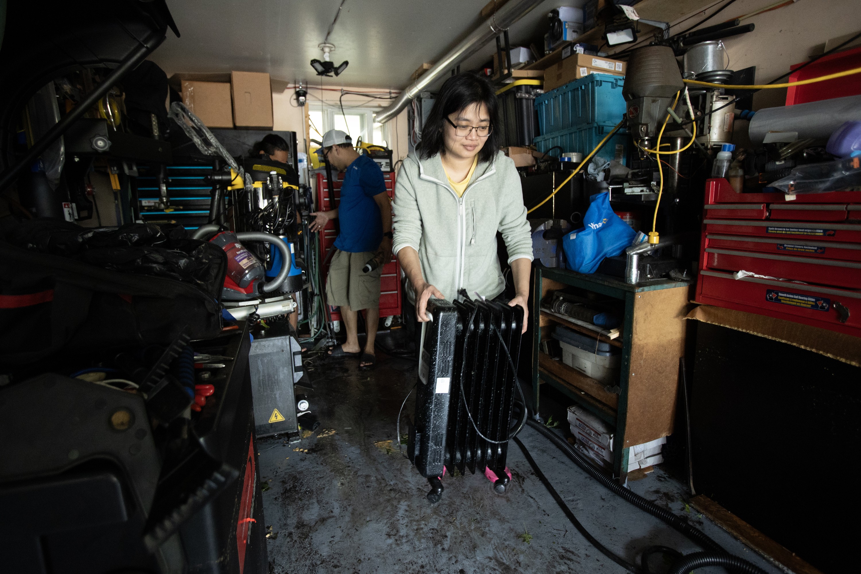 A family cleans out damaged items from a garage after flooding.