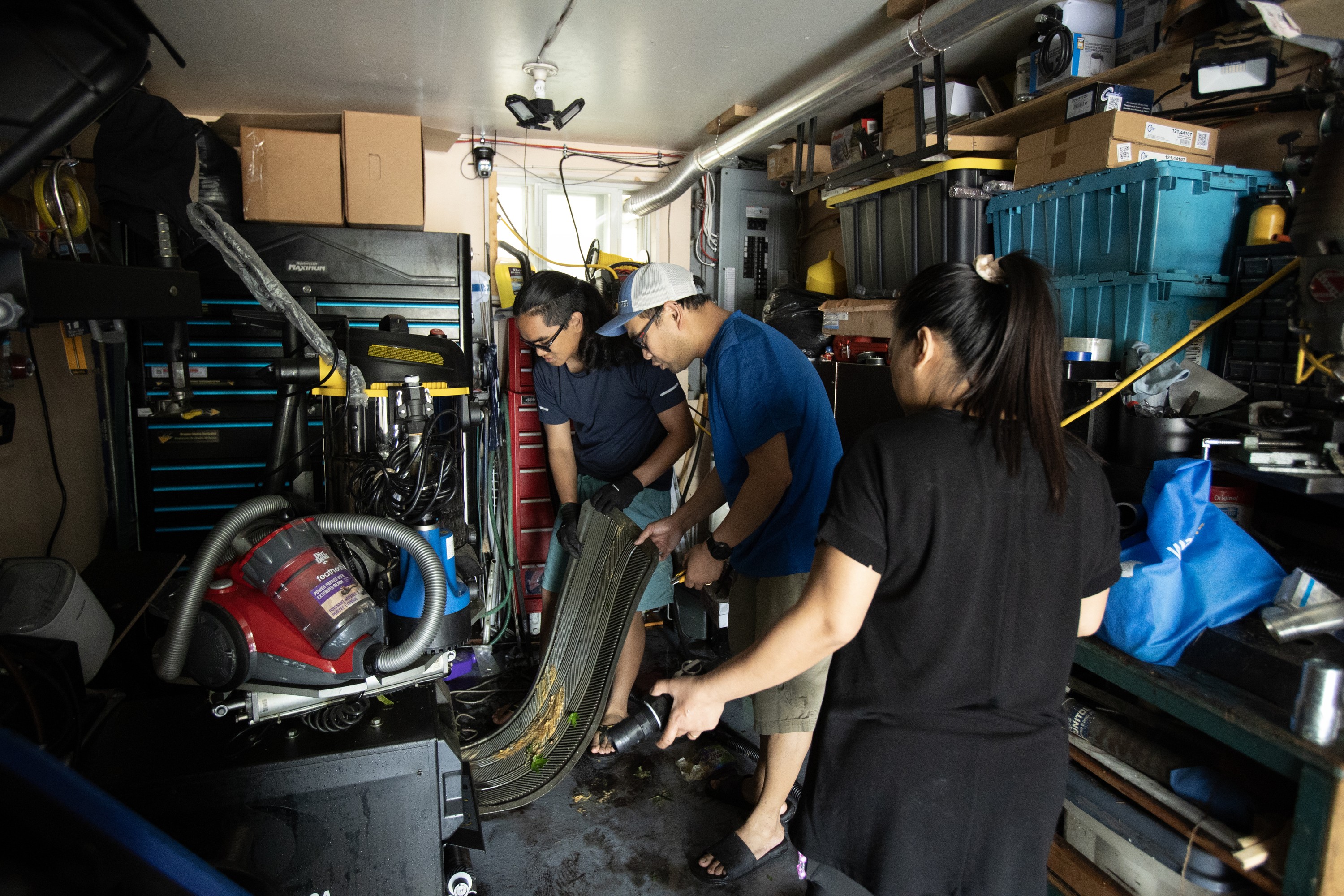 A family cleans out damaged items from a garage after flooding.