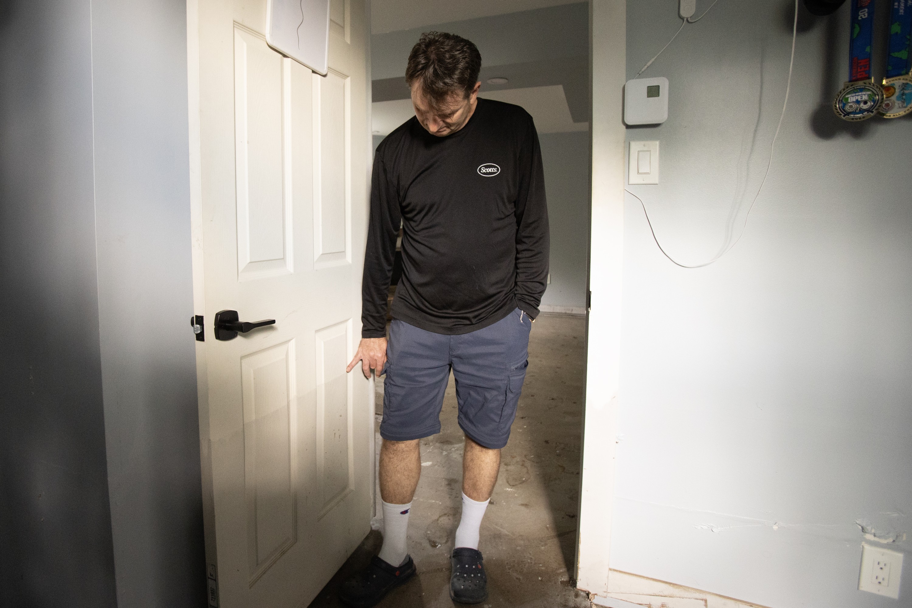A man points to marks on a basement door from flooding damage.