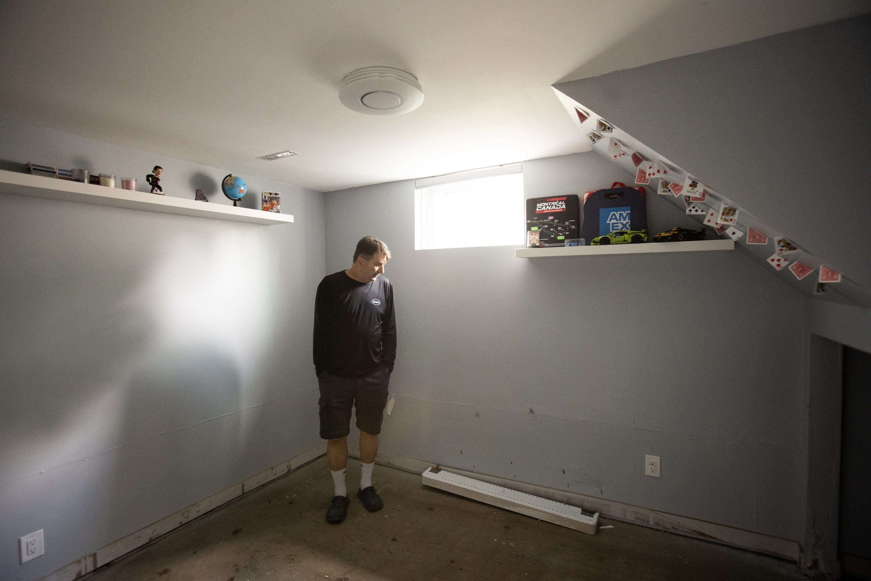 A man stands in the corner of a mostly barren basement room after flooding.