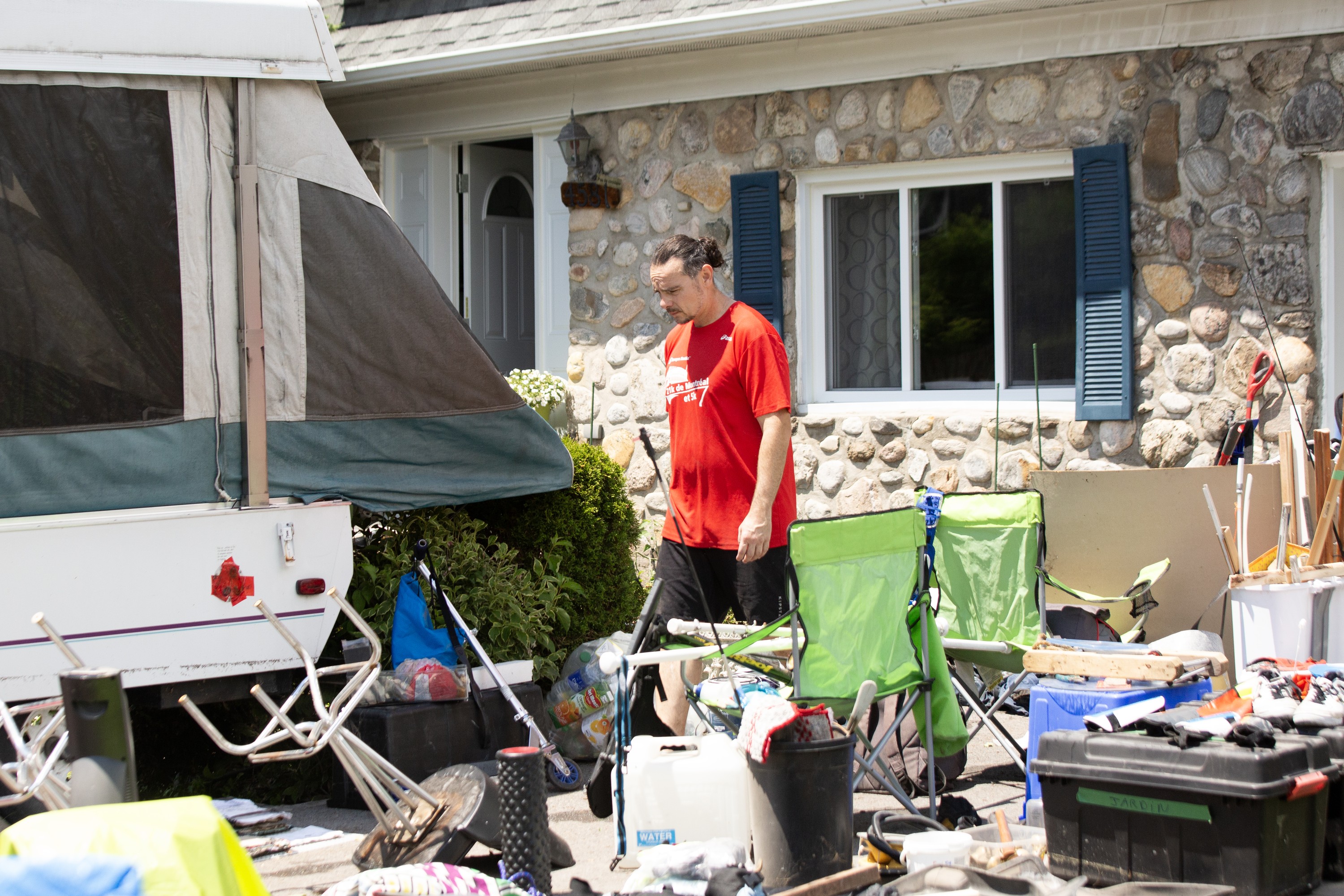 A man walks among flood-damaged possessions outside a house.