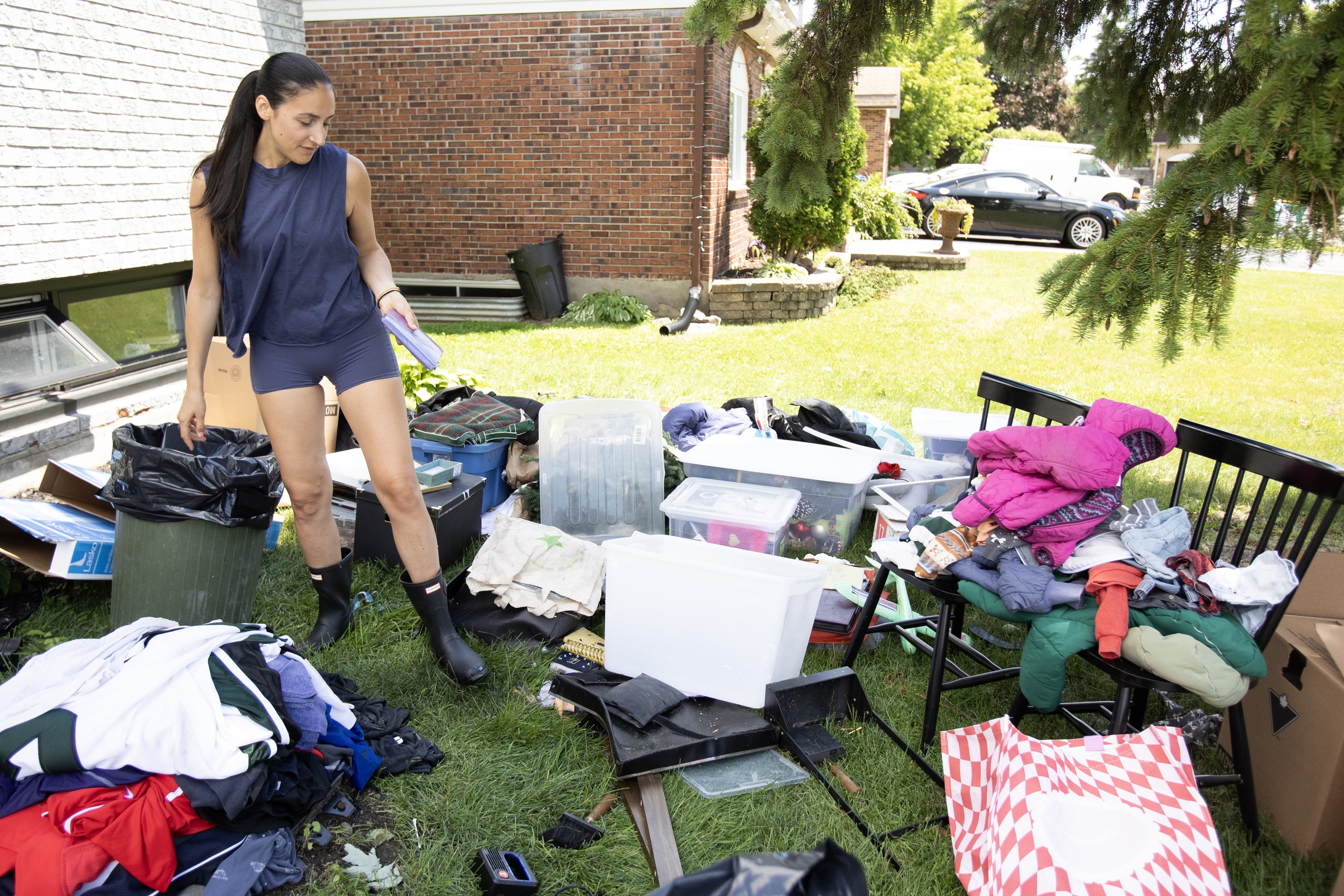 A woman walks among household items spread across a lawn.