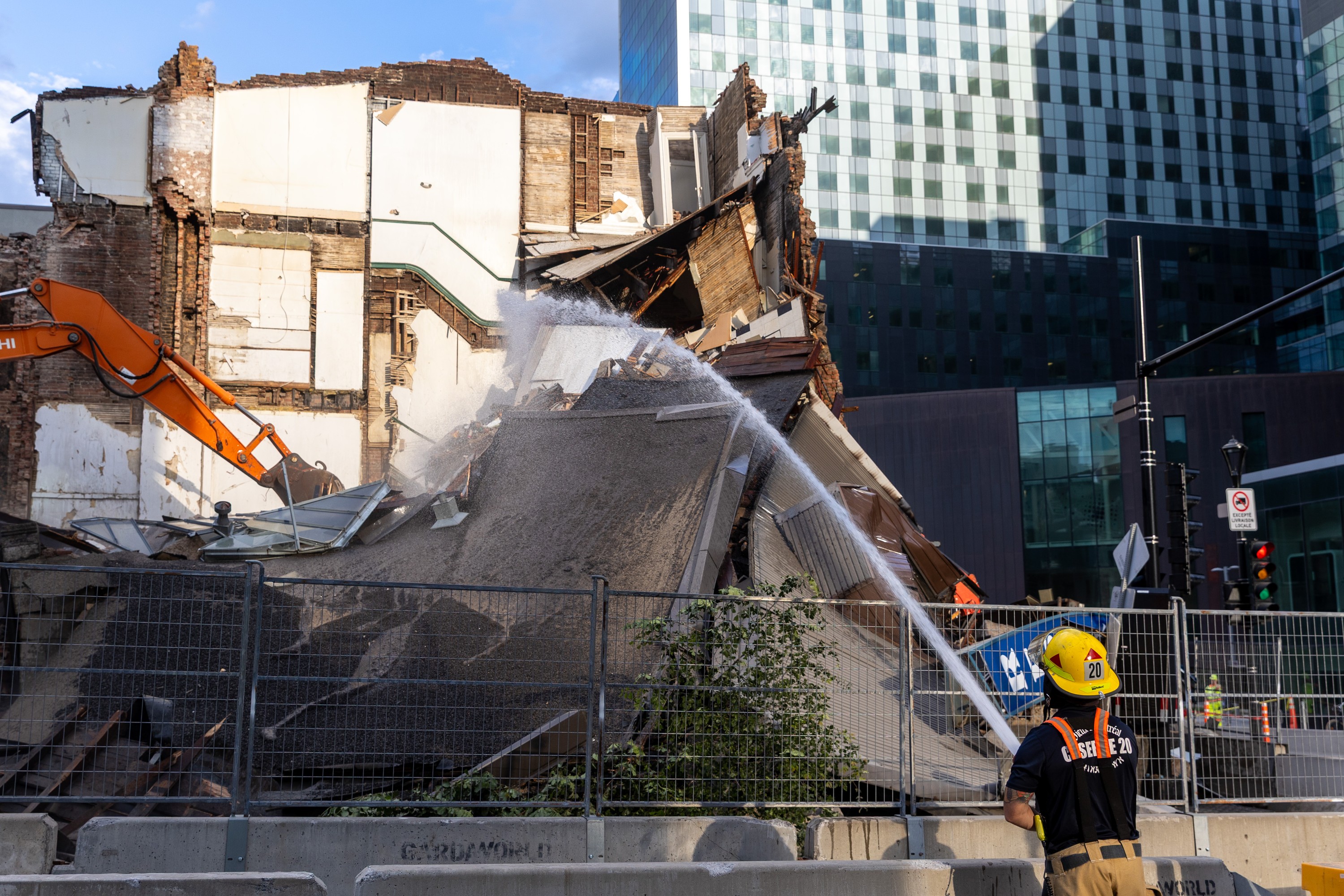 Montreal fire crews hose down the debris at the scene of a building collapse on the corner of René-Lévesque Boulevard and Saint-Denis Street in Montreal on Tuesday, June 23, 2026.