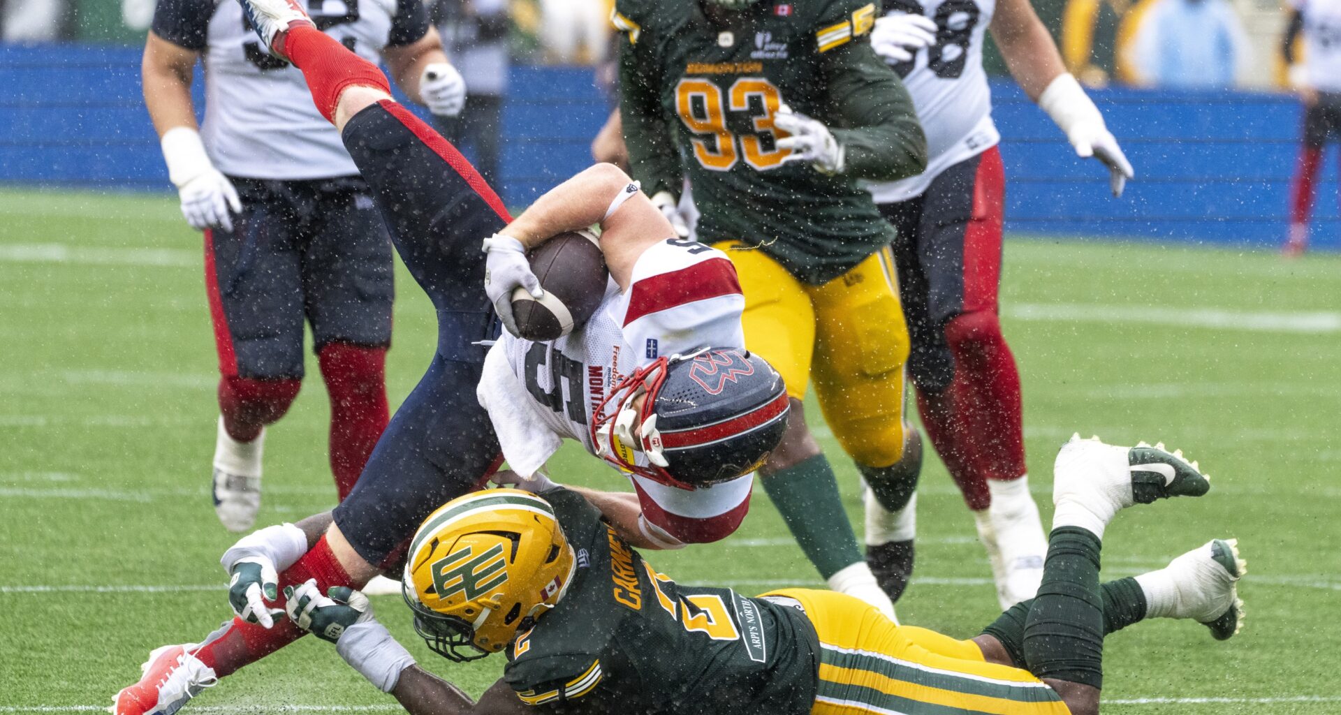Alouettes' Travis Theis is brought down by Elks defender Malik Carney on June 20 in Edmonton.