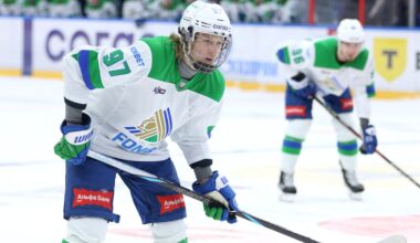 Close-up of Alexander Zharovsky wearing a white jersey with green trim on the ice during a KHL game.