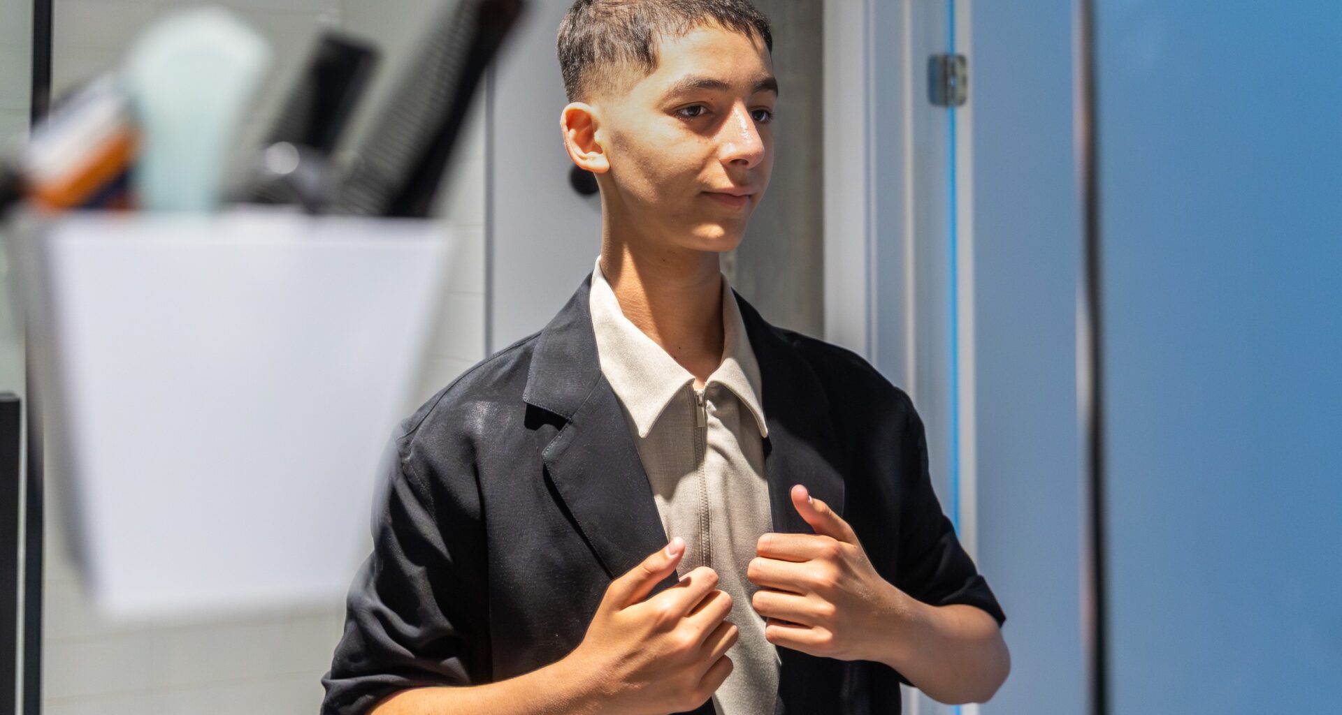 Adam Beaury, at home on Friday, June 19, preparing for his prom. He is wearing a light-coloured top and pants and a dark jacket. 
