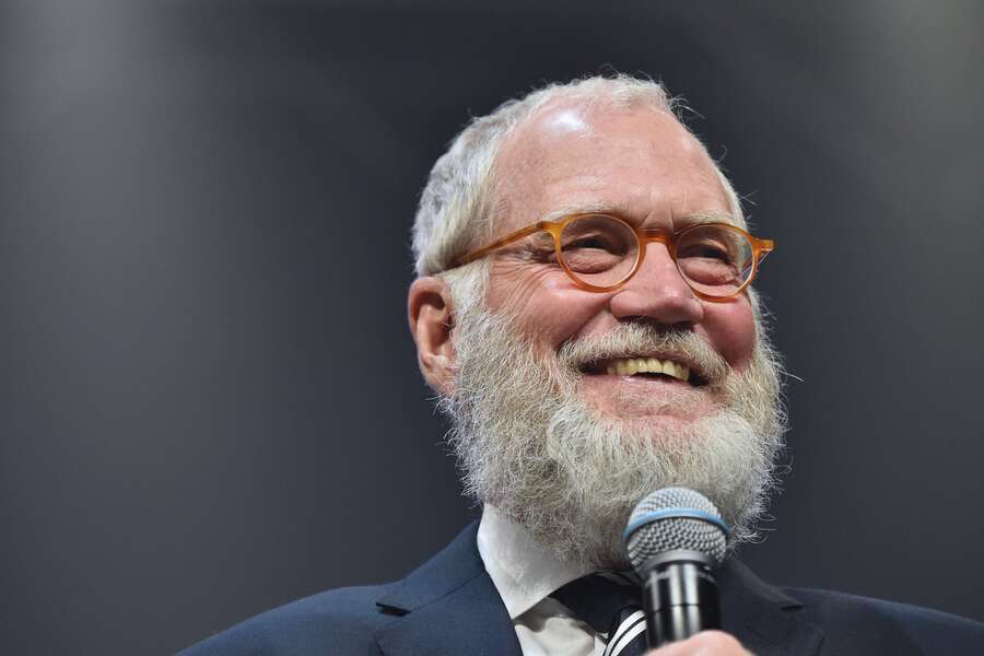 David Letterman grins as he holds a microphone