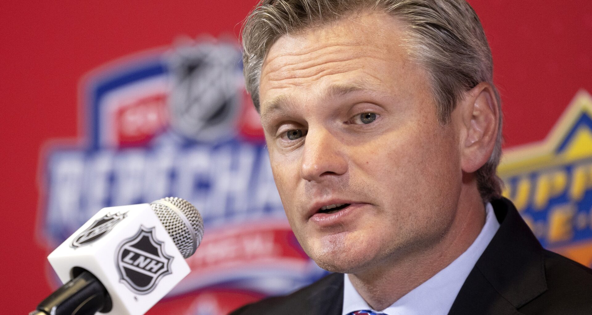 Nick Bobrov, co-director of amateur scouting for the Montreal Canadiens, speaks into a microphone with the French branding of the NHL