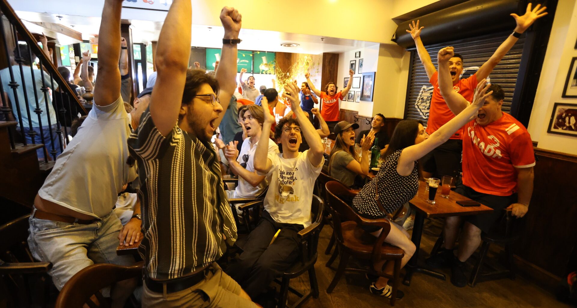 Fans at teh Burgundy Lion pub jump for joy after Canada's late goal against South Africa.