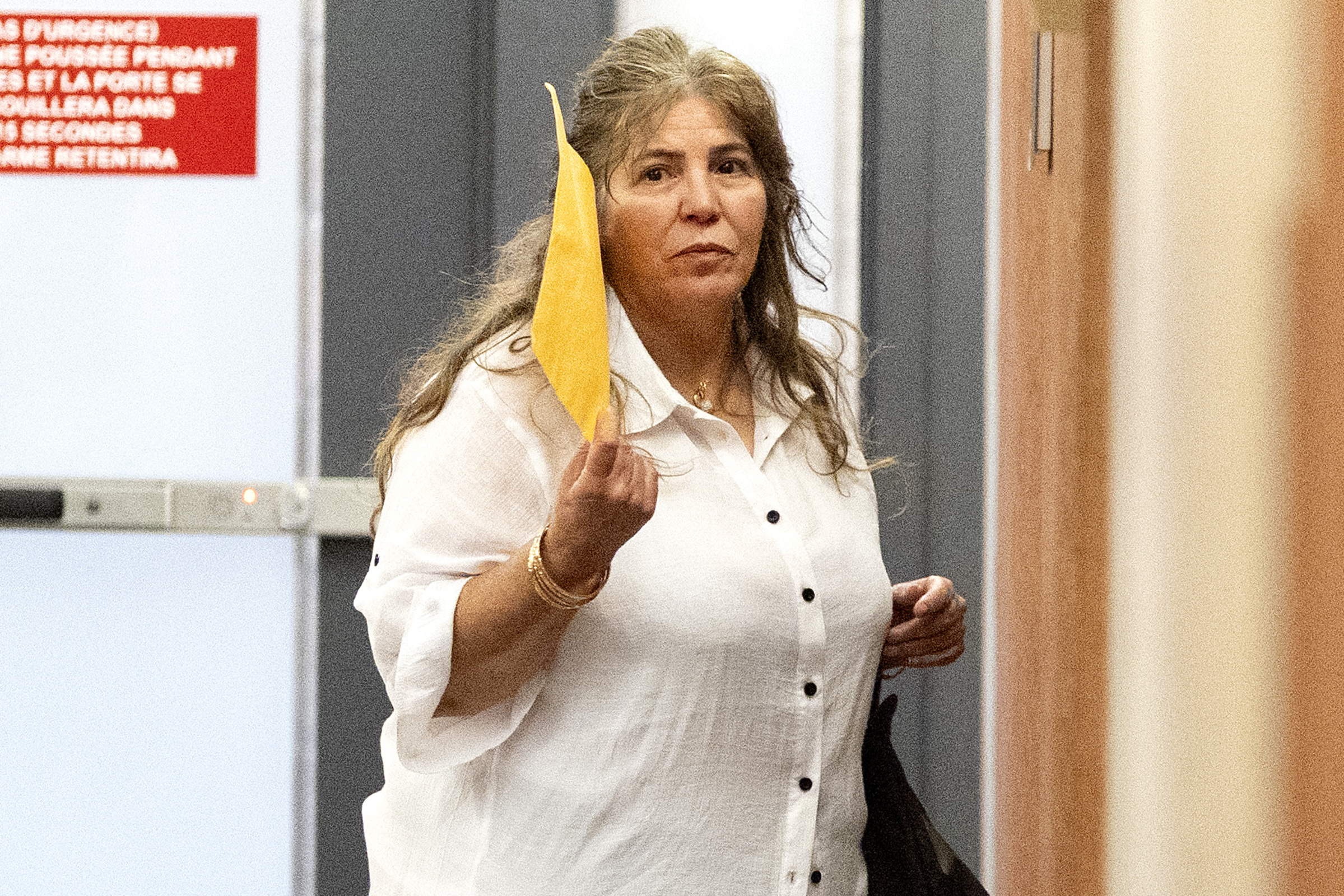 A woman holds an envelope as she stands in a courthouse hallway.