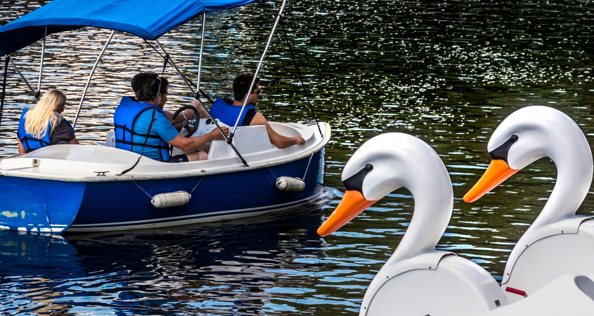A group of boaters take a ride on the water under the watchful eyes of a oair of duck boats.