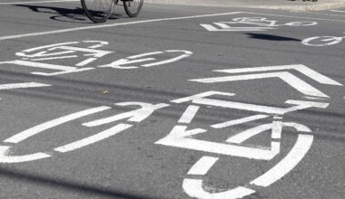 Closeup of bike-lane markings at an intersection. The wheels of a bike are visible at top left.