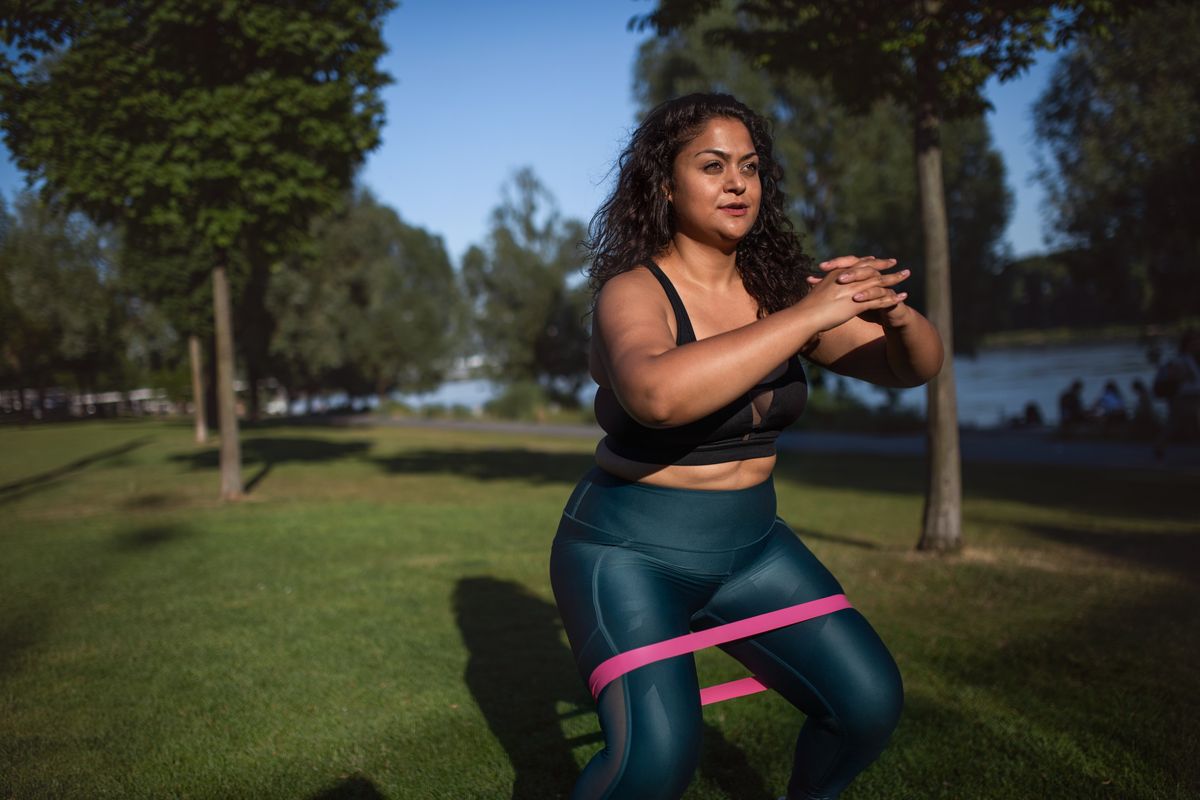 Woman with elastic band doing sport in city.