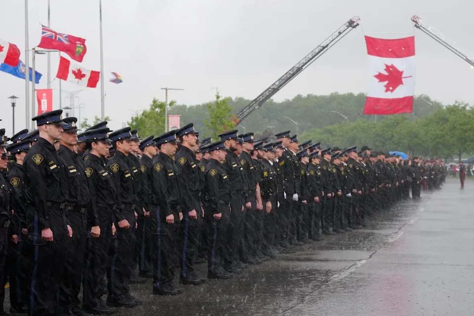 Police officers line up as rain falls before the start of the funeral service for OPP Provincial Constable Tarun Bali at the Mississauga Sports and Entertainment Centre in Mississauga, Ont., on Thursday, June 18, 2026.