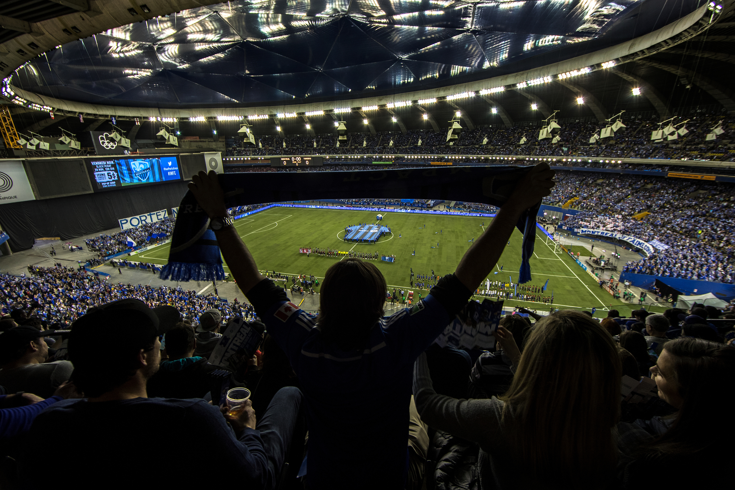 A fan holds up a scarf high up in the stands in Olympic Stadium, which is full for a soccer match.
