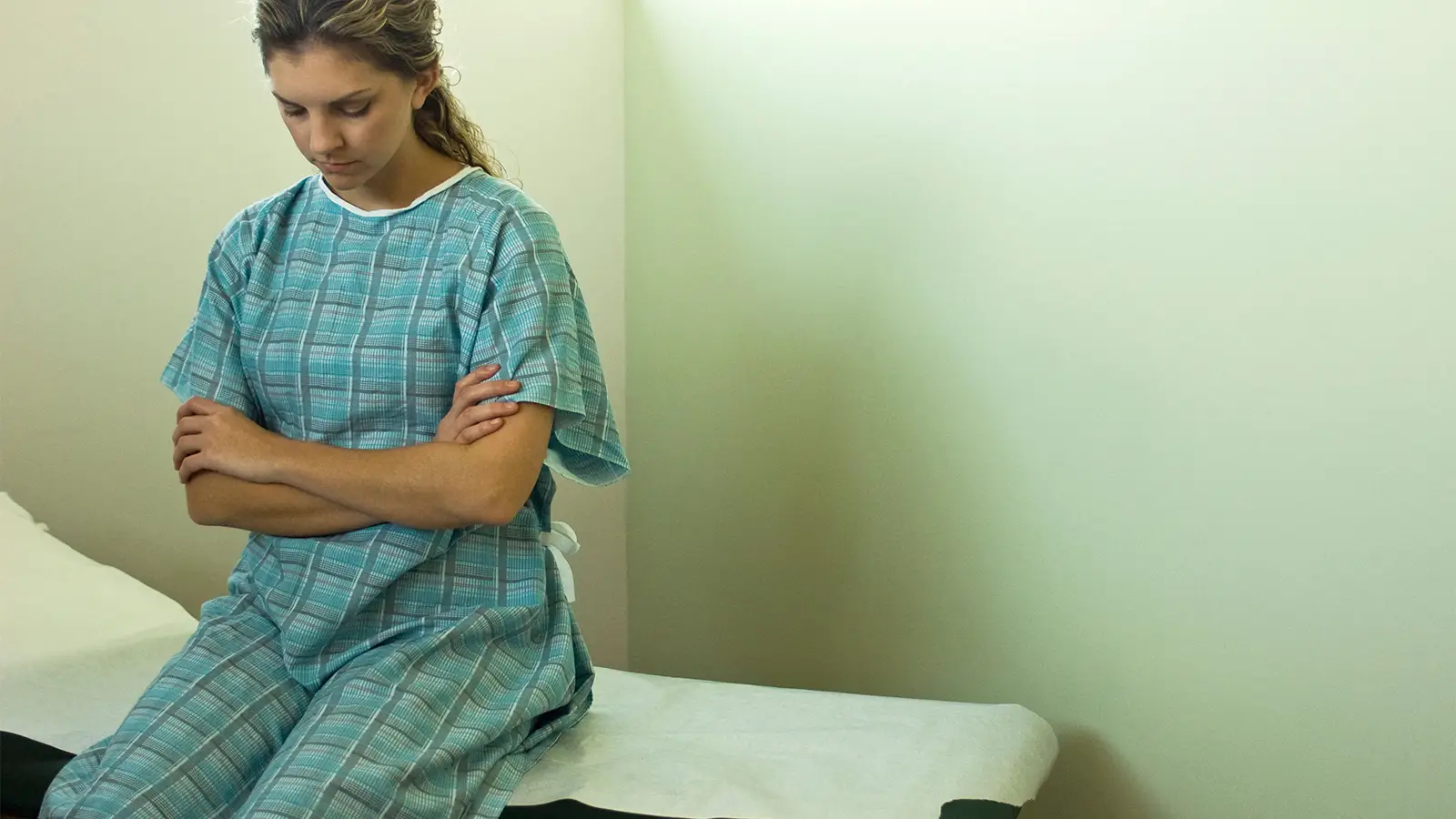 A photo of a woman sitting on an examination table.