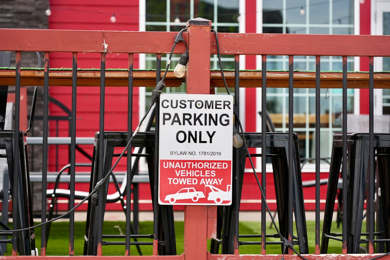 A parking sign warns non-customers could get towed if they park in this spot.
