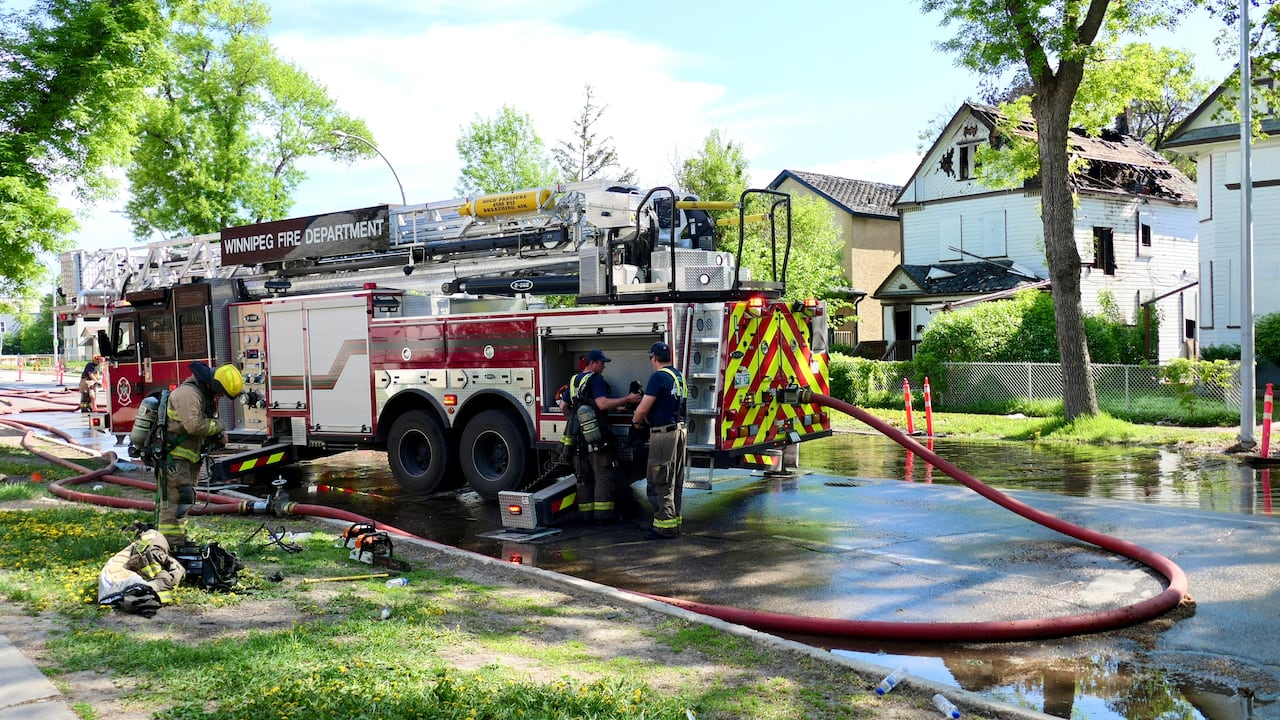 A fire truck is on a street covered in water. Some uniformed members are outside the truck.