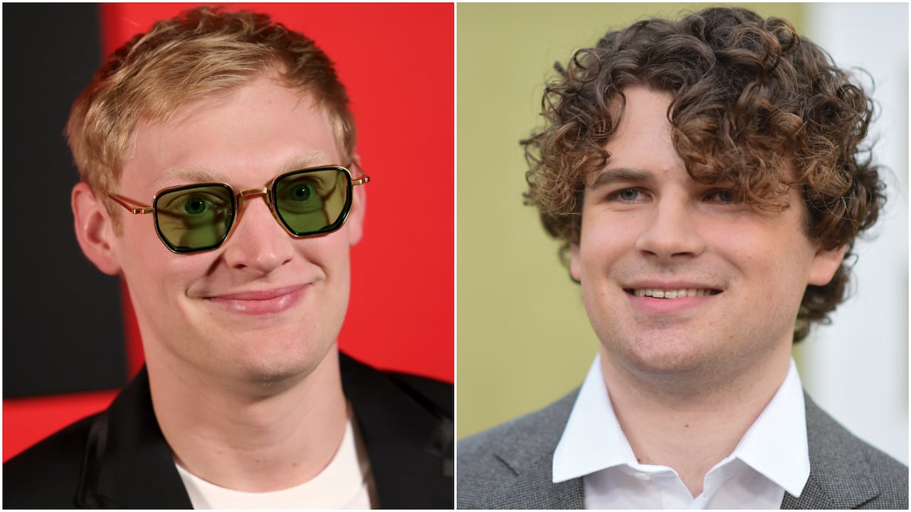 A composite shows two smiling young men: one with short blond hair wearing green-tinted glasses (left) and a curly haired man in a blazer (right).