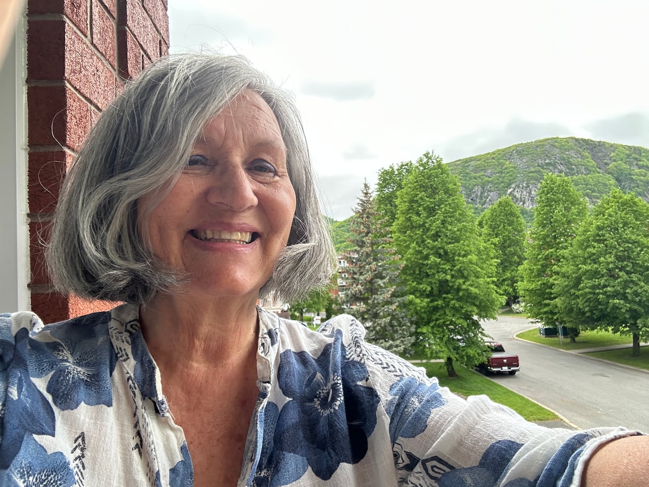 Elderly lady with white hair smiling on balcony