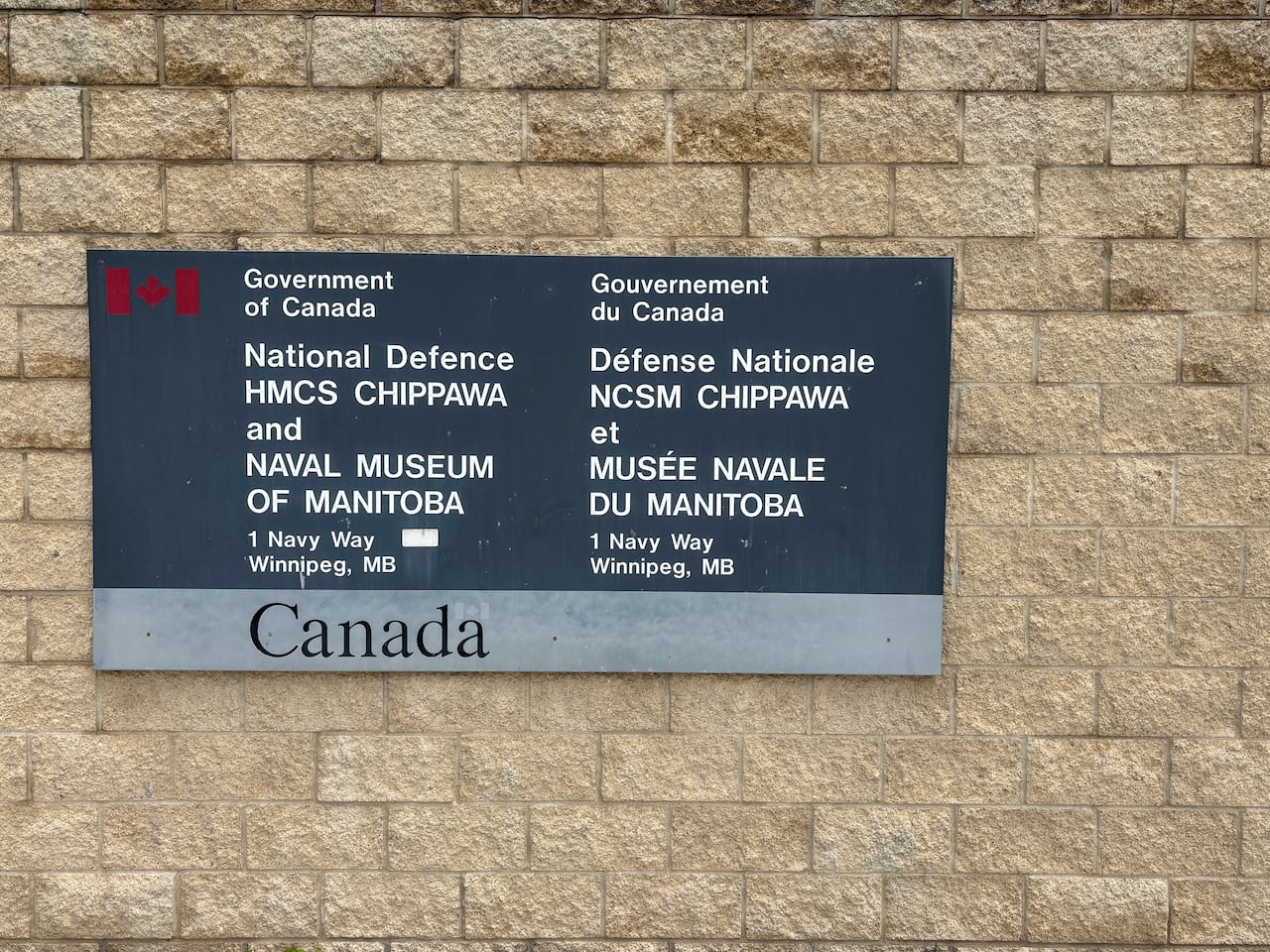 A sign is on a brick wall.
