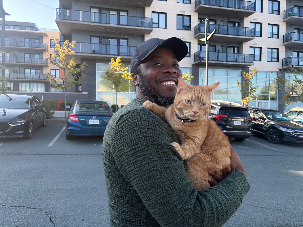 A man holds a cat near a condo