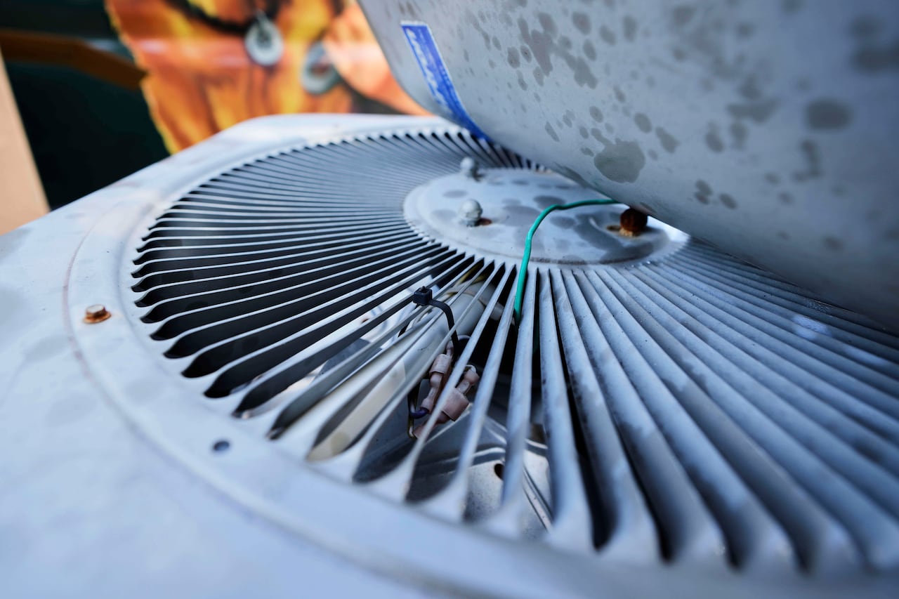 The old air conditioning condenser removed from a residential home sits on the front lawn as installation of a new HVAC system is competed, Wednesday, July 30, 2025, in Fate, Texas.