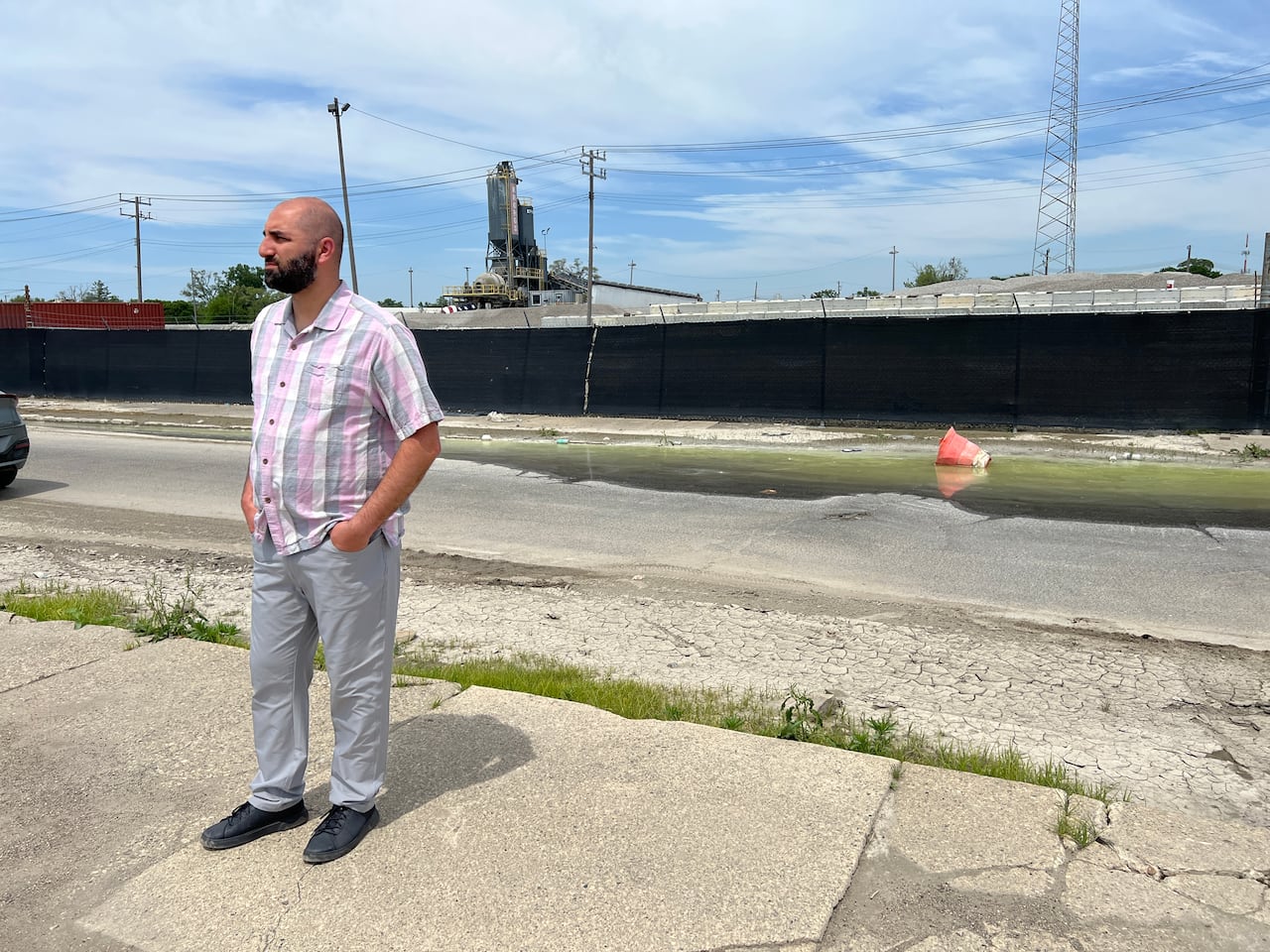 A man in front of a concrete facility and garbage in the street