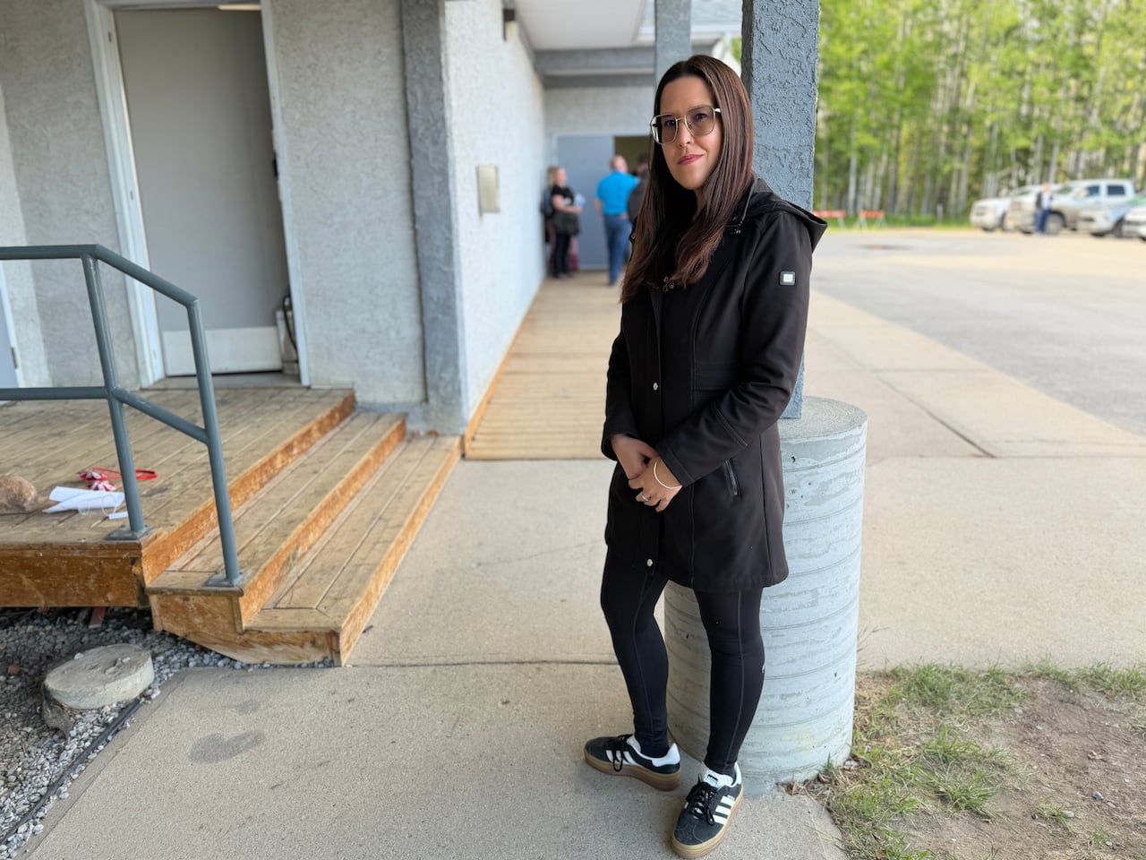 A woman stands outside of a community hall.