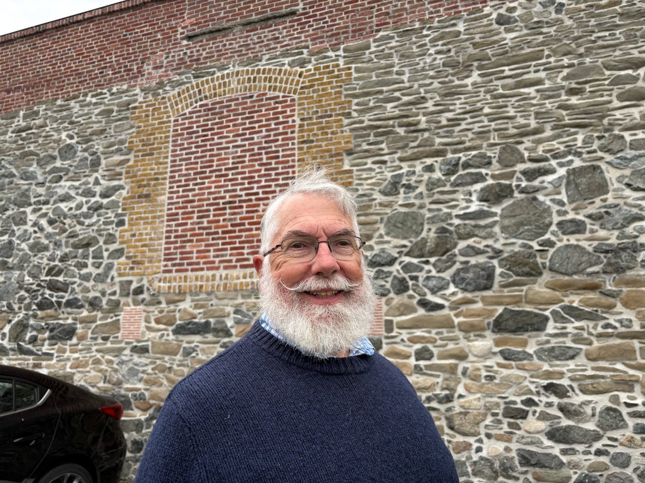 a man with a beard and mustache in front of a wall