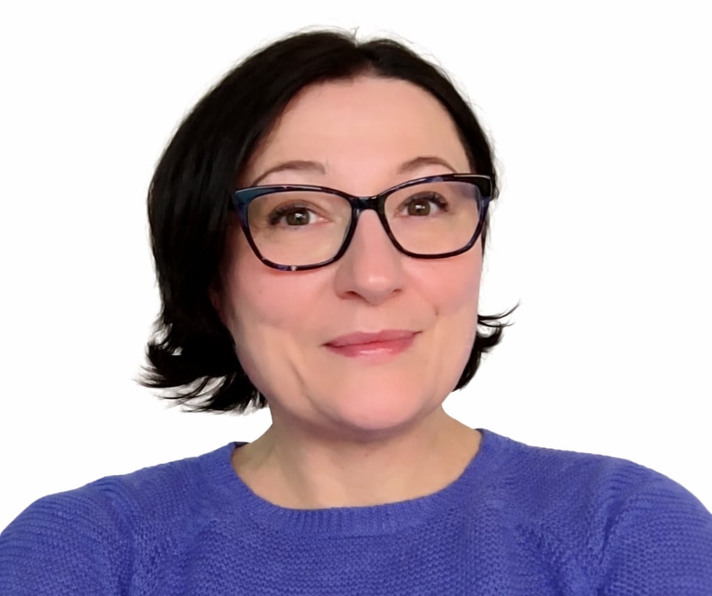 Woman wearing glasses in a blue sweater.