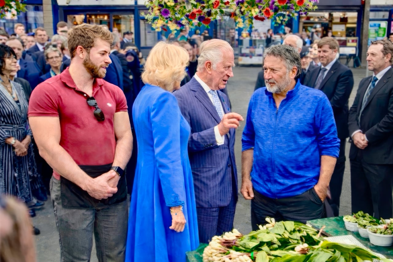A photo of three men and a woman surrounded by crowds in suits.