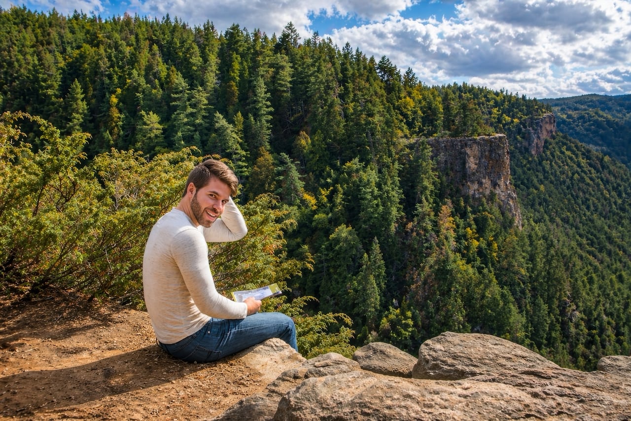 A man sits on the edge of a rock face.