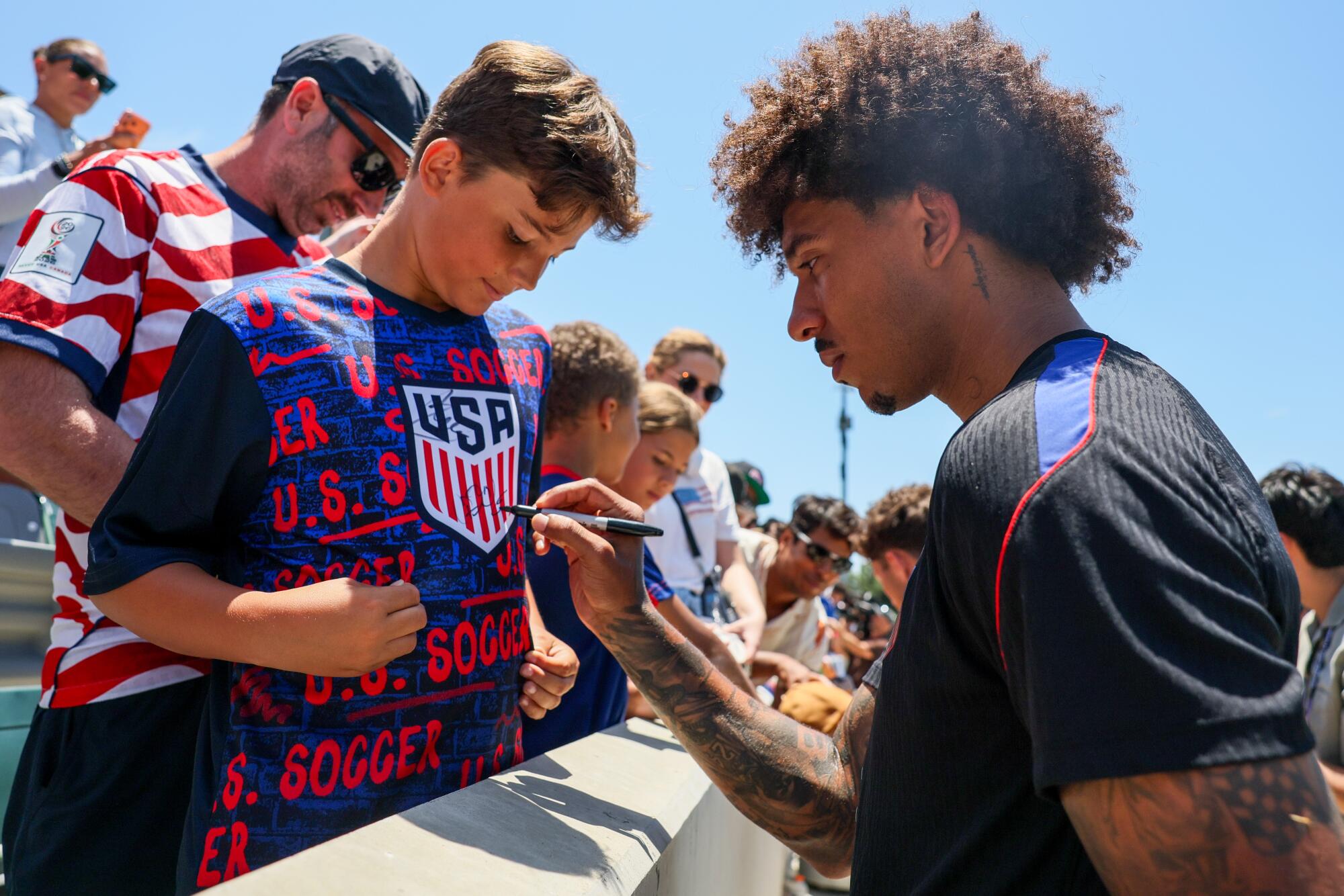 U.S. men's soccer player Chris Richards autographs the shirt of a young fan during a team practice Monday.
