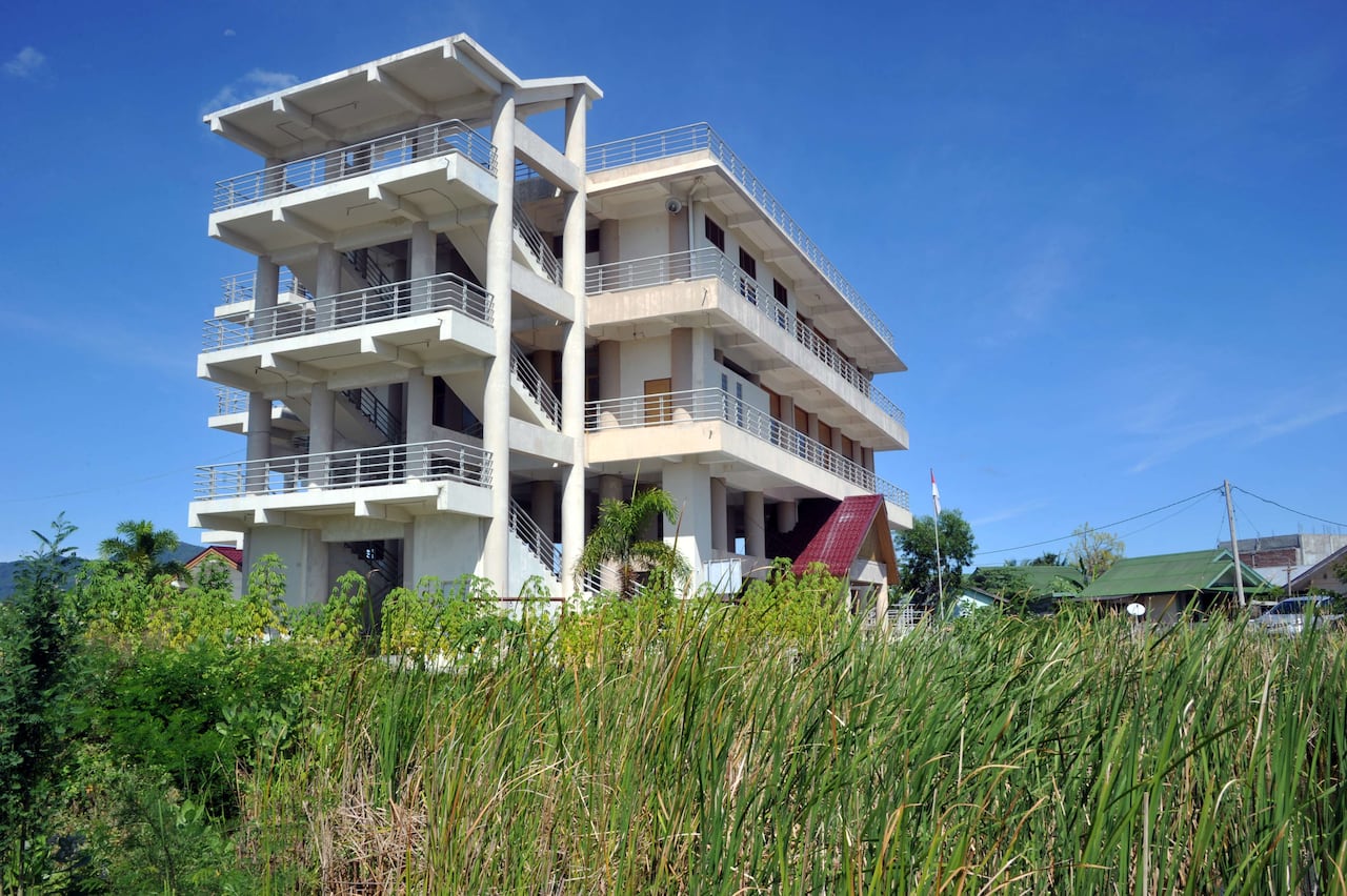 A four storey tsunami evacuation tower sits in a field.