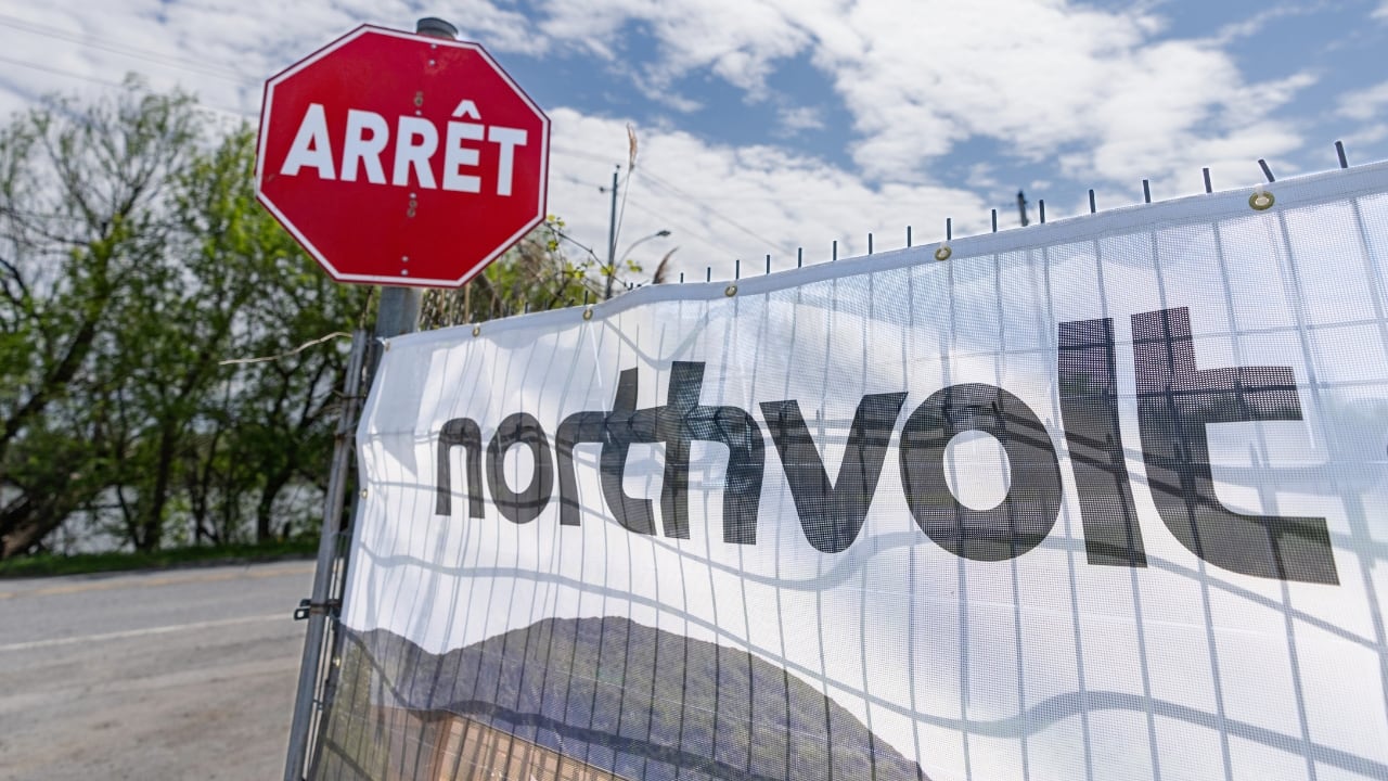 A sign on a fence reads northvolt, with a stop sign beside the fence
