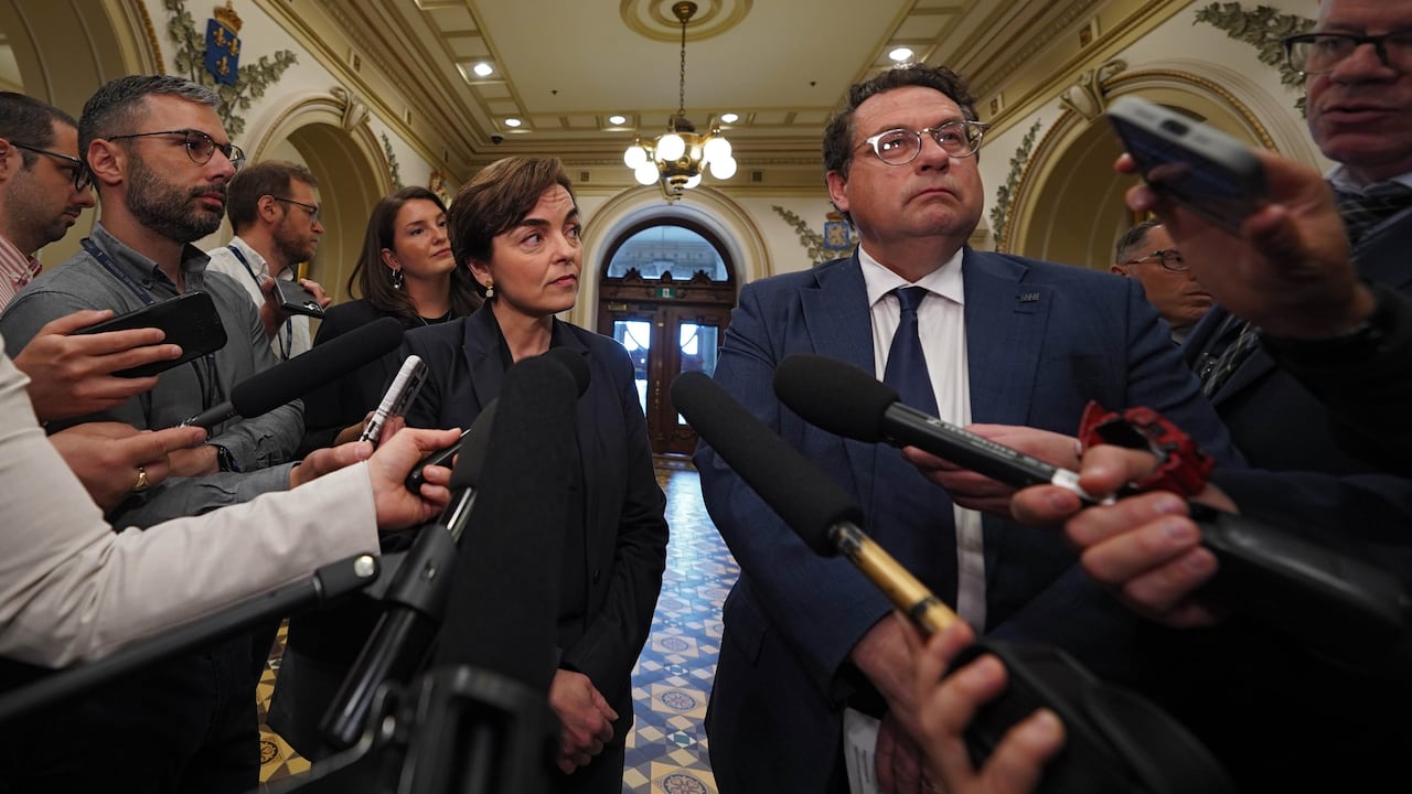 The Quebec premier and Minister of Economy, Innovation and Energy stand in front of a lot of microphones at the National Assembly.