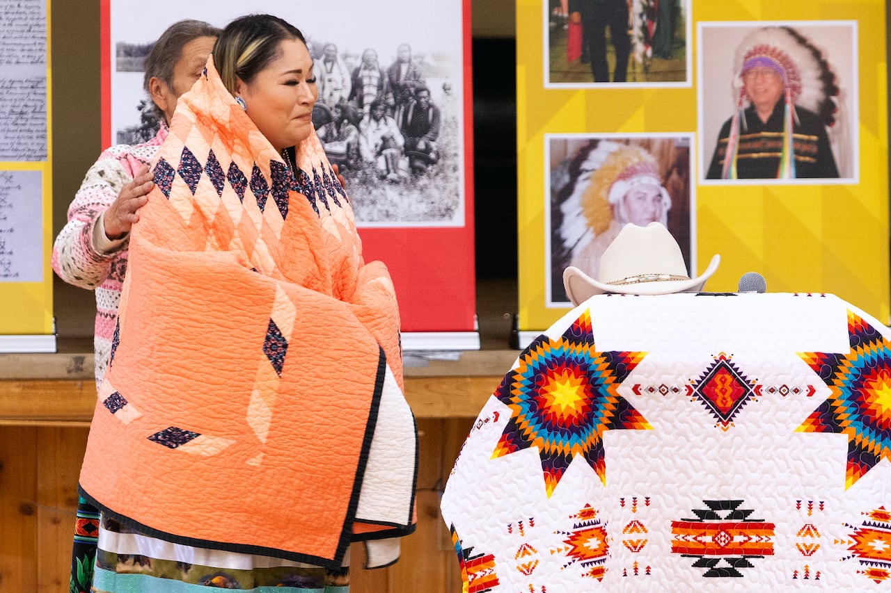 a young woman stands wrapped in a star quilted blanket, filled with emotion.